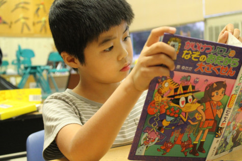 Second grade student Kota Hiroi reads a book after completing his drawing, coloring and writing assignment Nov. 21 at the Southern Indiana Japanese School. 