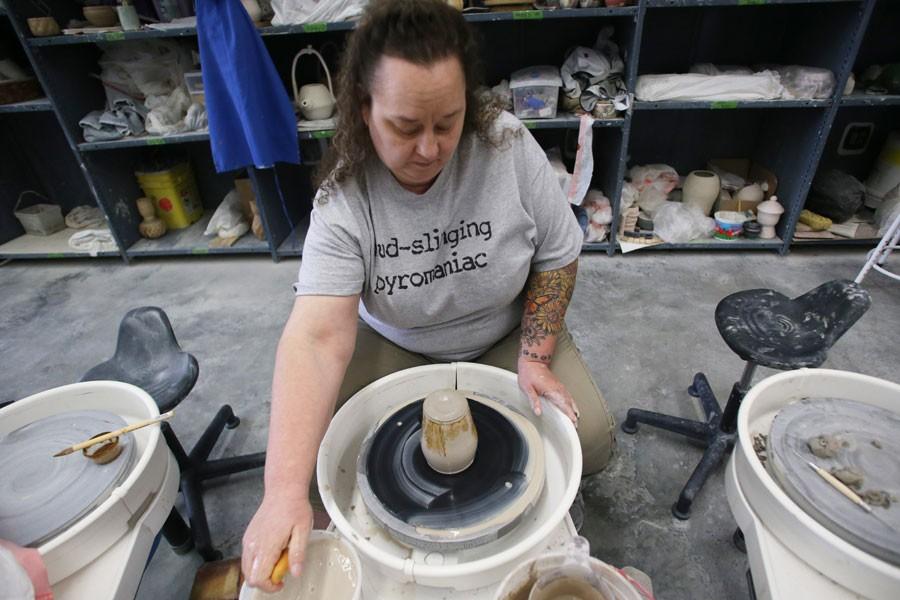 Sporting a shirt that reads “mud-slinging pyromaniac,” senior art major Denise “Mickie” Streets uses the pottery wheel as she works on a ceramic mug Monday in the Dowhie Ceramics Studio. Streets will have two of her ceramic sculptures shown in the Juried Student Art Exhibition April 3-May 1 in the McCutchan Art Center/Pace Galleries. 