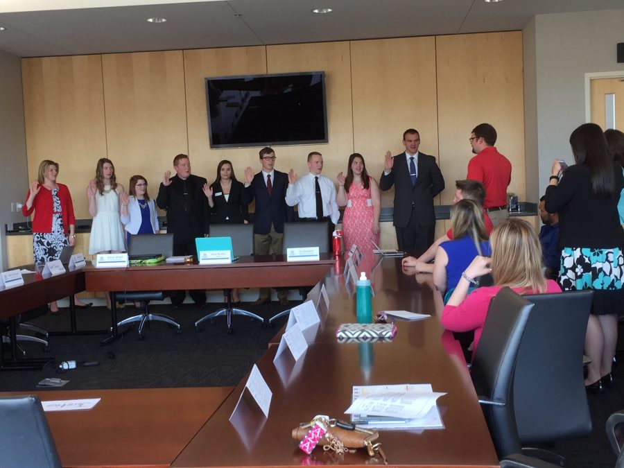 Chief Justice Jason Miner swears in the Student Government Associations 16-17 members while 15-16 President Alexa Bueltel takes a picture on her phone.