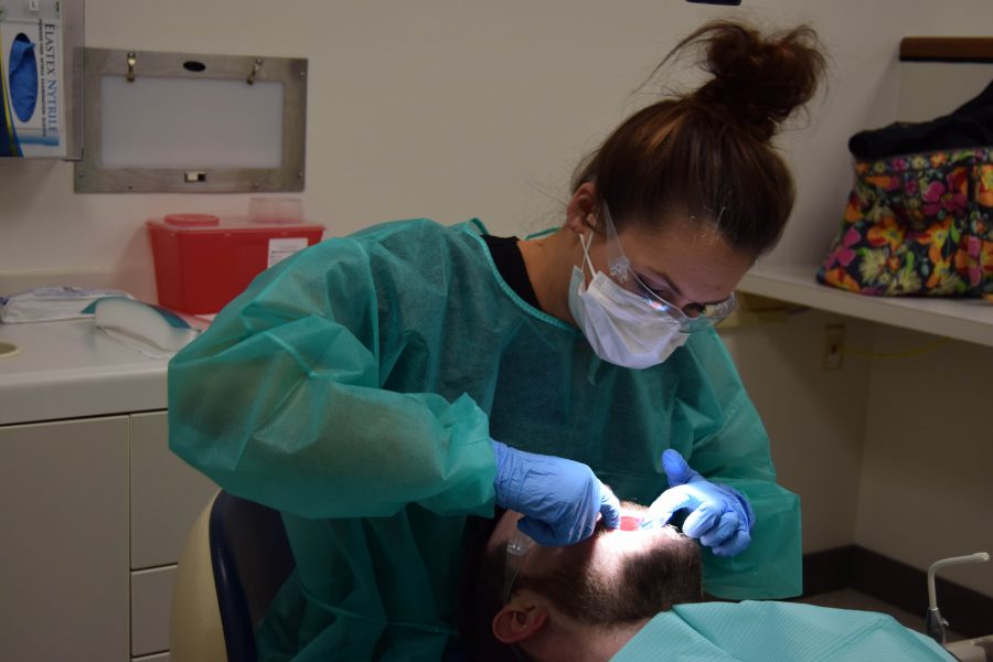Senior dental hygiene major Mackenzie Roll performs a check-up on veteran Michah Bahr. Bahr served in the U.S. Navy from 2004-2012 and gets his dental service for free from the USI Dental Hygiene Clinic. He said the program is “pretty cool” and he likes to help the dental students get real life experience when he comes in for his cleaning.