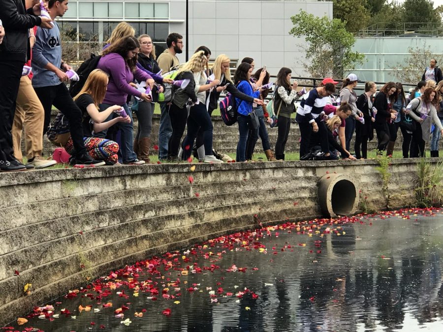 Students and guests release rose petals into Reflection Lake during the Flowers on the Lake event at the University Thursday evening. The event was held to spread awareness for victims of domestic abuse within the community. 