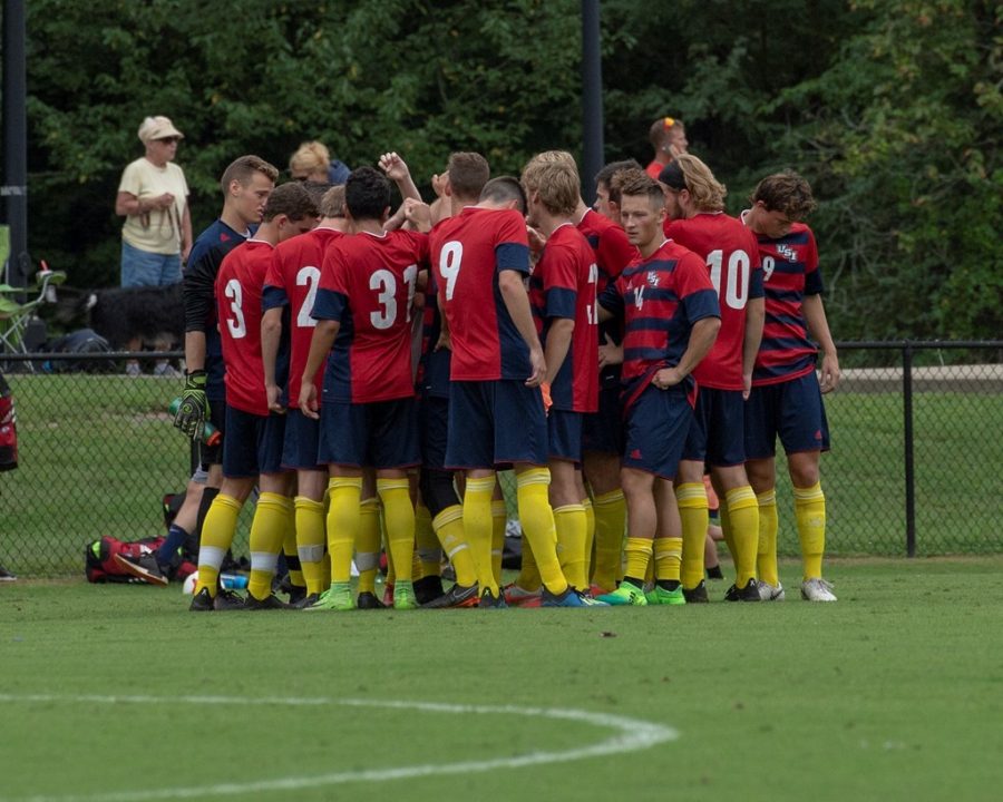 The mens soccer team huddles together during a game. 