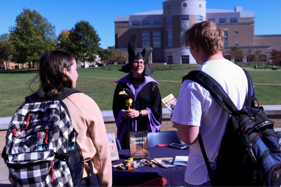 Melissa Stacer, professor of criminal justice Studies, talks to two students about her books, dressed as Maleficent.