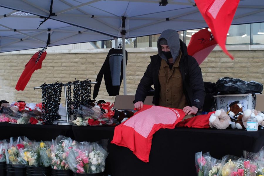 Conner Adams, a member of the student alumni association, waits outside selling flowers, shirts and other gifts to attendees.