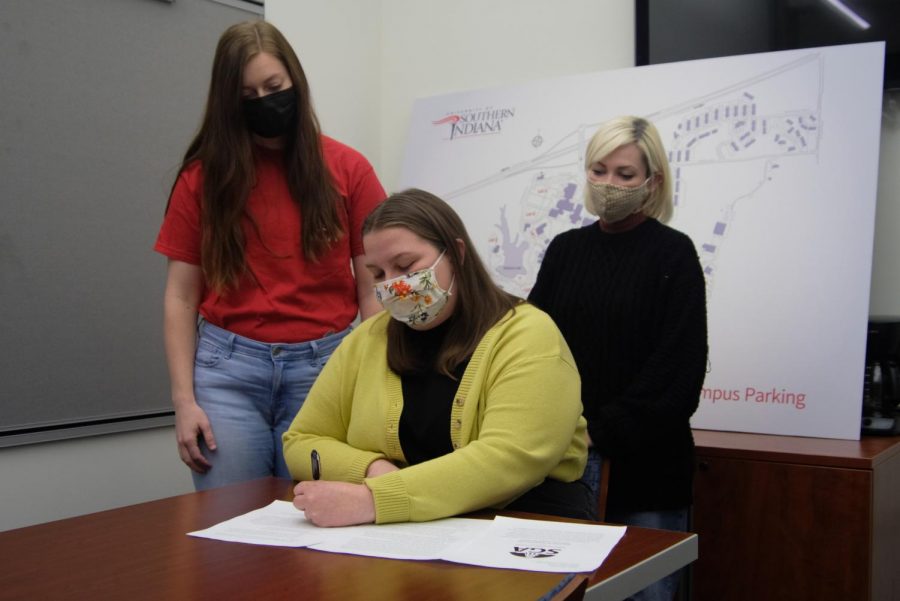 Anna Ardelean, president of Student Government Association, signs a resolution regarding the campus busing situation Monday. Erika Uebelhor (back left) wrote the letter of support and Haviland Wyant (back right) was the second signature on the resolution Monday. 