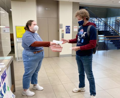 Anna Ardelean, Student Government Association president, hands a KN95 mask and COVID-19 information to Christian Holman, a senior sociology major, Thursday in the University Center West. SGA has been distributing COVID-19 masks in University Center West Wednesday and Thursday.  