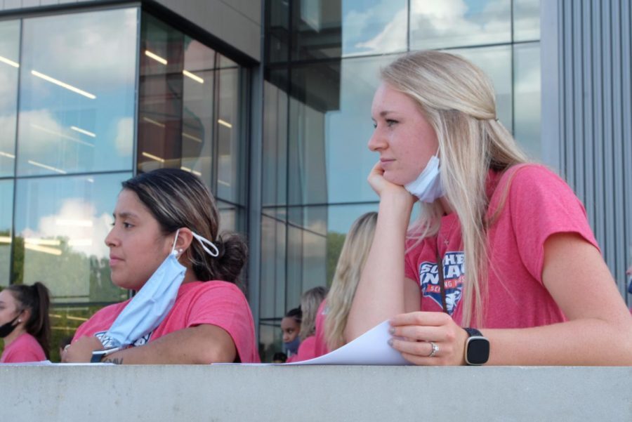 Gina Flores, junior exercise science major, and Elizabeth Dauby, senior exercise science major, lower their masks as they wait outside for the athletics facility  celebration to begin Sept. 16, 2021.  