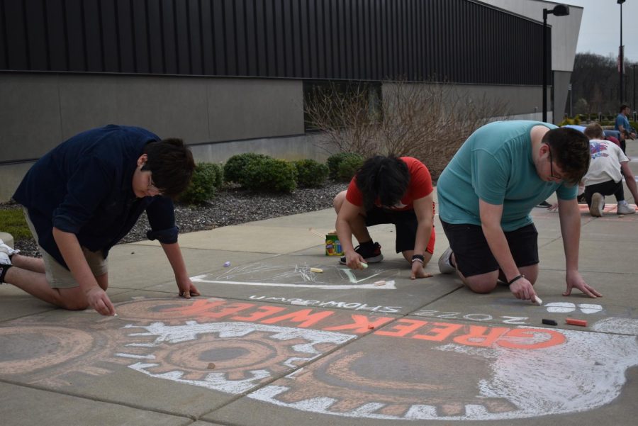 Agustin Martinez, sophomore computer science major, Mark Sorg, junior exercise science major, and Hunter Weaver, junior sociology major work on the chalk mural for Lambda Chi Alpha. The mural features gears with a skull in the background.