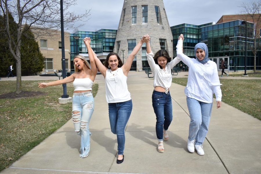 (From left to right) Skye Fuller, a junior public relations and advertising major, Jordan Teusch, a junior business administration major, Lily Hubbard, a freshman graphic design major and Hanoo Alqahtani, a senior international graduate business administration major, holding hands on campus and taking pride in their femininity. The four women participated in a photo shoot for the print issue Women of USI on March 15. 