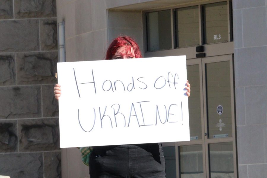 Anna Gallagher, a freshman with a  psychology major and a minor in music, holds up a sign that states Hands off UKRAINE! while at the protest on Wednesday, March 2nd.