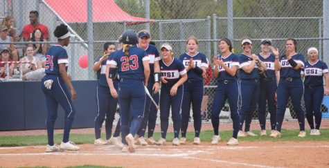 The universitys womens softball team run to home plate to congratulate Jordan Rager, junior infielder, after her home run in the second inning on Sunday. 
