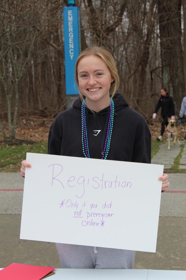 Shelby Vaughn, sophomore exercise science major, holds up a sign to show participants where to register for the Out of the Darkness Stop Suicide Walk.