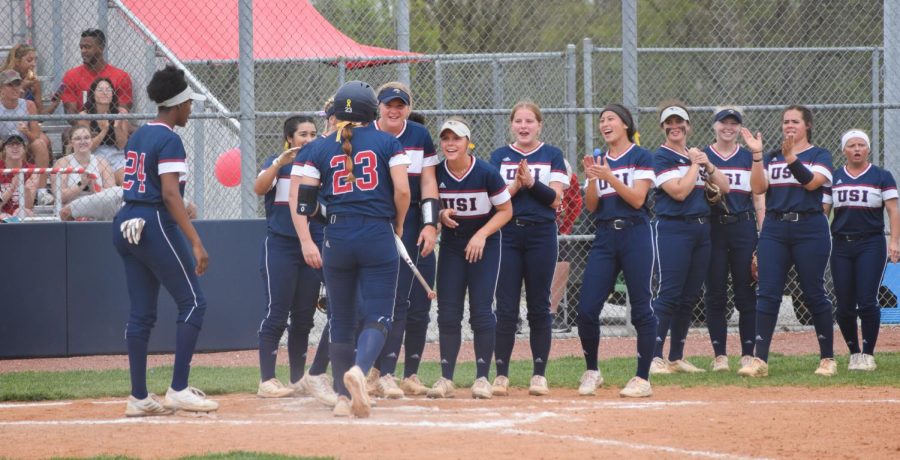 The university’s women’s softball team run to home plate to congratulate Jordan Rager, junior infielder, after her home run in the second inning on Sunday.