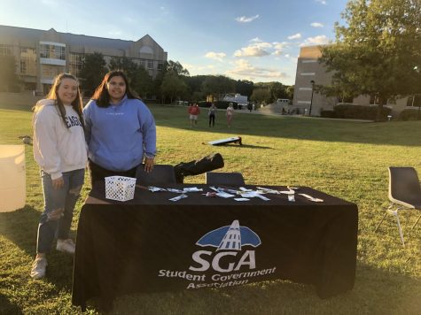 Taegan Garner, SGA president, and Adrianna Garcia, administrative vice president for the Equity, Diversity, and Inclusion committee for SGA, smile in front of their SGA table. The table was set up at the Latinx Heritage Festival to welcome students with stickers. (Photo by Alyssa DeWig)