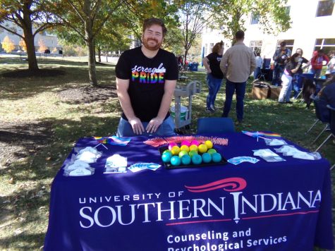 Aaron Pryor, assistant director of Counseling and Psychological Services, shows off his "Screagles Pride" T-shirt during PrideFest on The Quad Friday. The table featured many free items for students, including stress balls with QR codes that can be scanned to book a counseling appointment. (Photo by Alyssa DeWig)