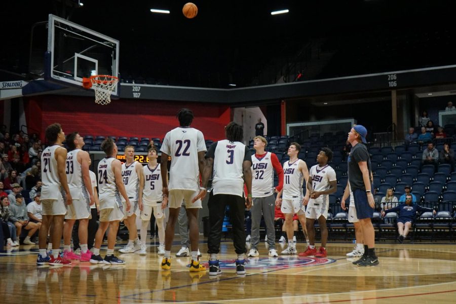 The mens basketball team watches a student shoot the ball during the free-throw contest at the 2022 Midnight Madness event Thursday in the Screaming Eagles Arena.