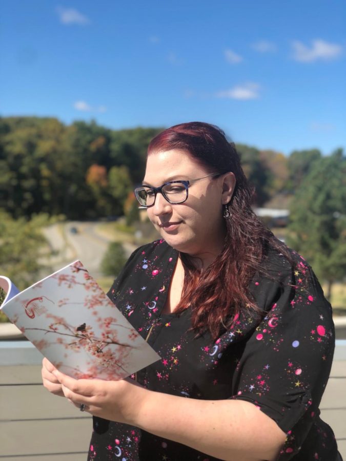 Denise McKenzie reads volume 10 of Fishhook, the most recent volume, on the balcony of the Liberal Arts Center. This is McKenzies first year as an editor for FishHook. 