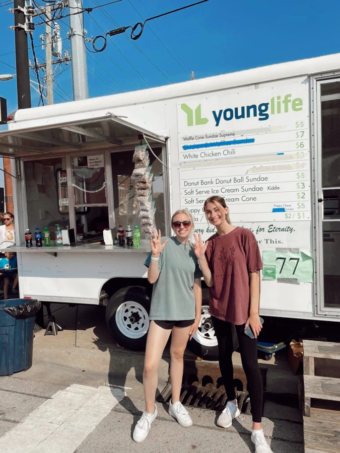 Ashlyn Thompson and Faith Peak imitate the Young Life symbol in front of their Fall Festival booth. The hand symbol is a Y and L for Young Life. The Young Life booth has been #77, located in the same spot, for the past 20 years. (Photo courtesy of Raychel Guiser)