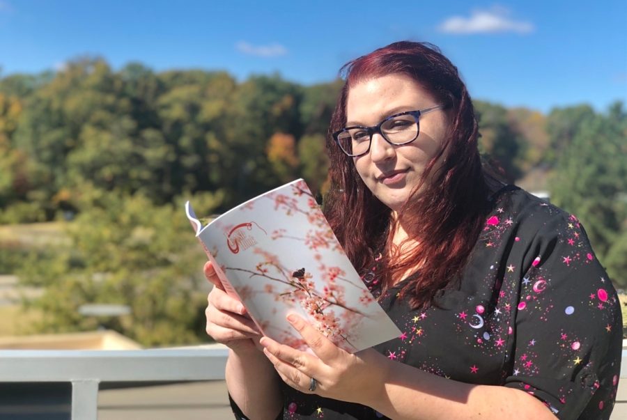 Denise McKenzie reads volume 10 of Fishhook, the most recent volume, on the balcony of the Liberal Arts Center. This is McKenzies first year as an editor for FishHook.
