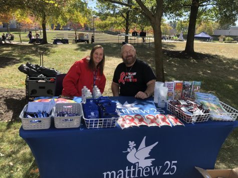 Representatives from Matthew 25 flash smiles on The Quad for PrideFest Friday. Matthew 25 is a non-profit organization that provides support and free testing for those with HIV. Free condoms, stickers, merchandise and pamphlets were available for attendees. (Photo by Alyssa DeWig)