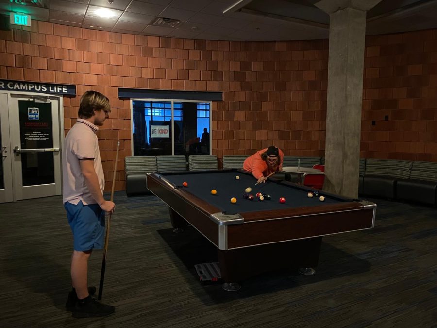 (Left to right) John McLain, freshman kinesiology major, and Pierce Howard, senior political science major, play pool in the basement of University Center East during the afternoon power outage Thursday.