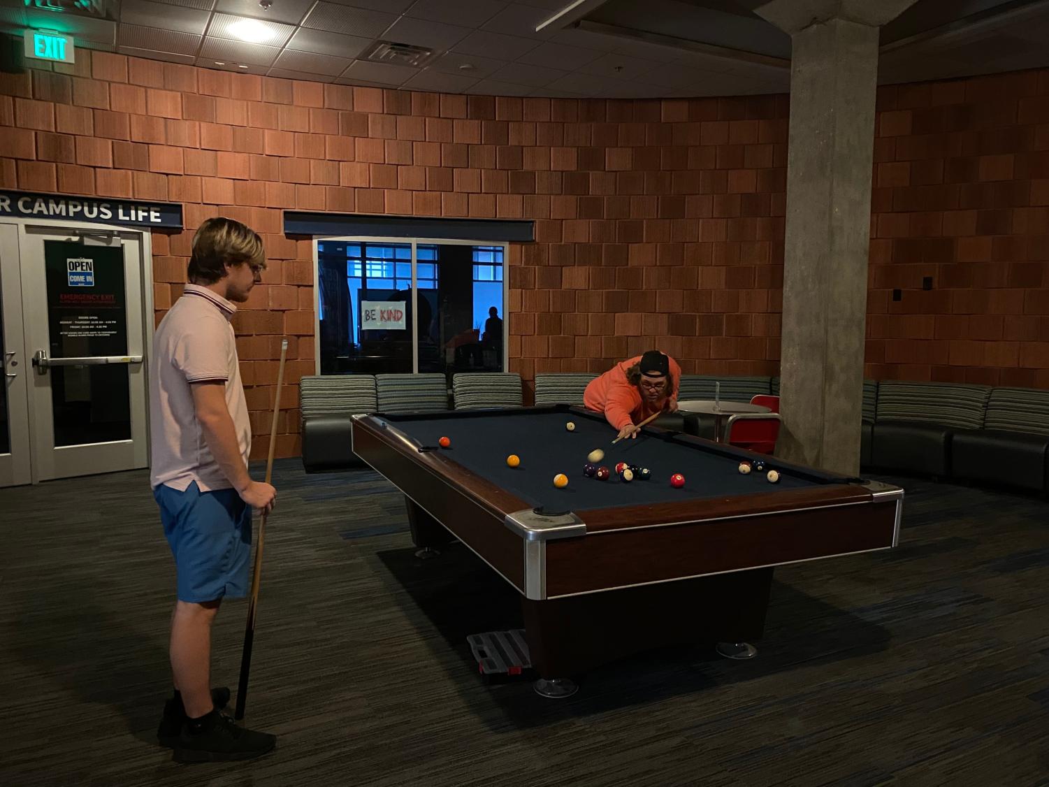 (Left to right) John McLain, freshman kinesiology major, and Pierce Howard, senior political science major, play pool in the basement of University Center East during the afternoon power outage Thursday. (Photo by Shelby Clark)