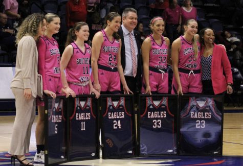 The 2022-2023 womens basketball seniors pose with their framed jerseys and the womens basketball coaching staff Saturday at the Senior Night Ceremony in the Screaming Eagles Arena.
