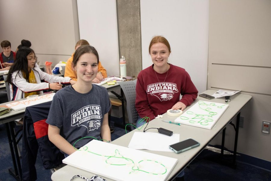Caroline Bossman, freshman nursing major, and Courtney Gates, freshman mathematics and statistics major, smile with their finished designs at the Neon Signs event Thursday in University Center East (Photo by Crystal Killian).