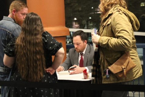Craig Fehrman, USI alumnus and author of "Author in Chief: The Untold Story of Our Presidents and the Books They Wrote," signs a copy of his book for attendees during his reading and book signing event outside the USI Performance Center Wednesday. (Photo by Bryce West)