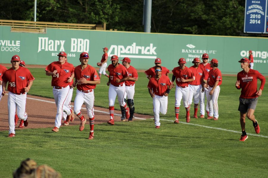 The mens baseball team runs across the field to the dugout Wednesday before the game against Oakland City University at the USI Baseball Field.
