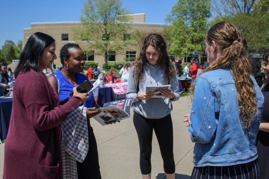 Attendees hold copies of Unmasked: The Story of How COVID-19 Affected the University of Southern Indiana at the Unmasking USI event Monday on The Quad.