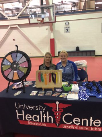 Lorie Reynolds-Thomas, LPN Lead, and Haley Wade, practice manager for the Health Center, smile from behind the University Health Center booth at Condom Carnival Wednesday in the Recreation, Fitness and Wellness Center. The booth featured a true and false game, a display of various-sized condoms, female condoms, dental dams and booklets. (Photo by Alyssa DeWig)