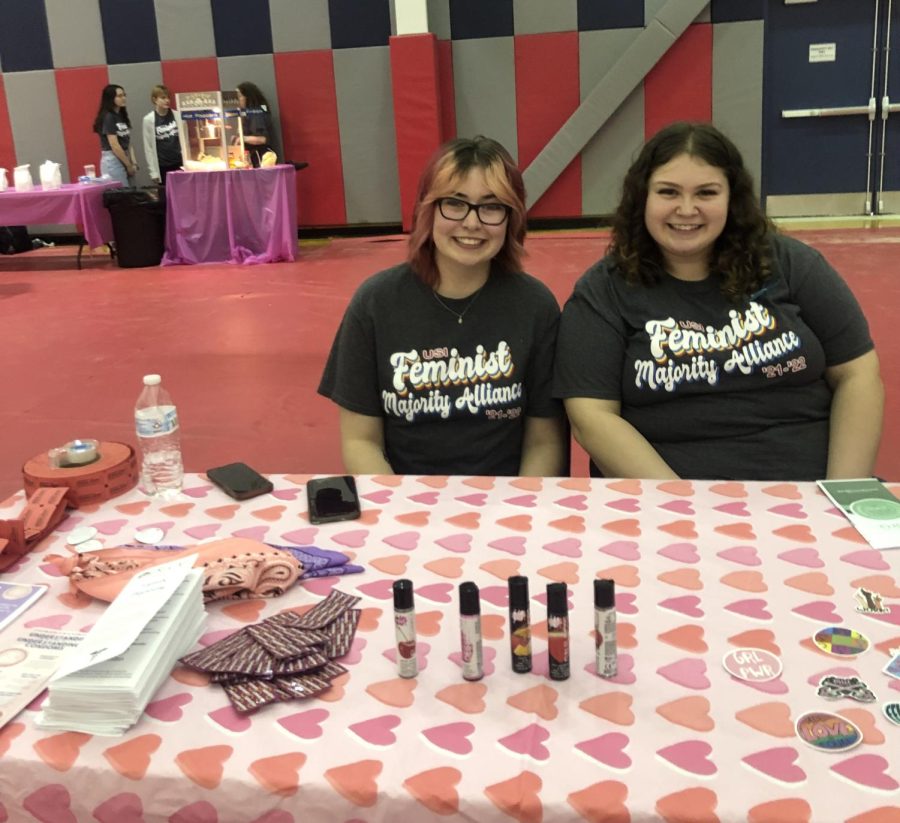 Mariah Hief, junior psychology major, and Katelyn Runyan, president of Feminist Majority Alliance, smile behind their booth at Condom Carnival Wednesday in the Recreation, Fitness and Wellness Center. The booth featured stickers, lube and booklets promoting sexual education and health. (Photo by Alyssa DeWig)