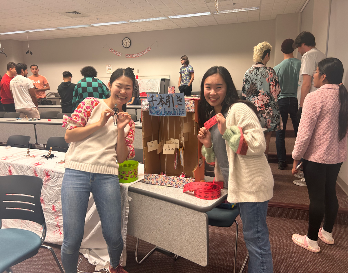 Anh Truong, sophomore pre-nursing major, and Ayno Hosoya, sophomore pre-nursing major, pose with a DIY version of the Senbonbiki game at Aki Matsuri hosted by the Japanese Club Thursday in the Liberal Arts Center.