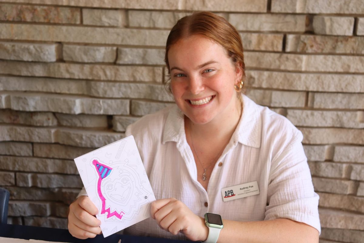 Audrey Fox, president of the Activities Programming Board, smiles with her incomplete birthday card for Archie at the Color Your Spirit event hosted by APB Tuesday in the University Center Breezeway. Fox worked on the birthday card while other students participated in the event.