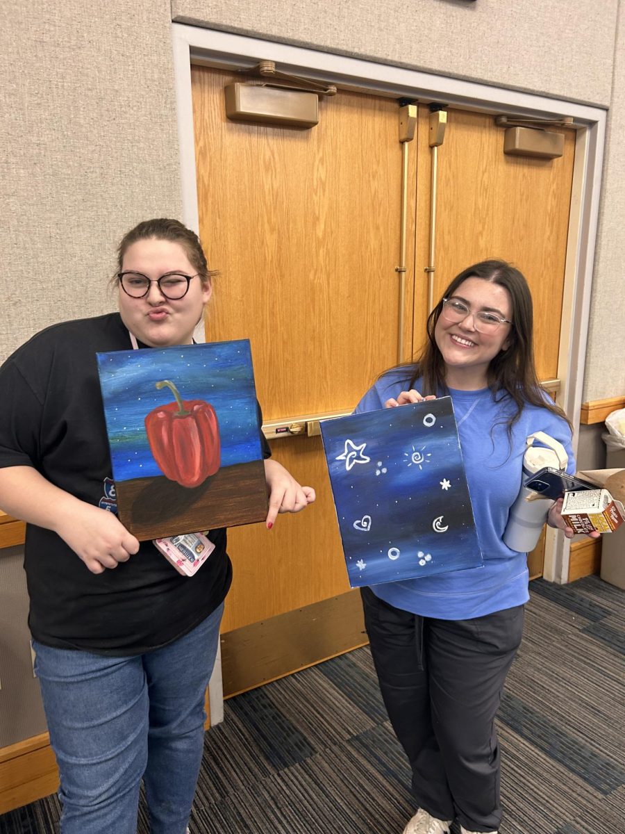Payton Henn, sophomore art education major, and Whitney Wagler, junior English education major, smile with their completed paintings at the Activities Programming Boards Cookies and Canvas event Monday in Carter Hall. 