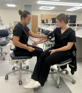 Ashlyn Peach, senior dental assisting major, and Madison Wagner, sophomore dental assisting major, take turns checking each other’s vitals before class Sept. 18. After receiving a $6 million leadership gift from alumnus Wayne Kinney and his family, the College of Nursing and Health Professions will be renamed the Kinney College of Nursing and Health Professions.