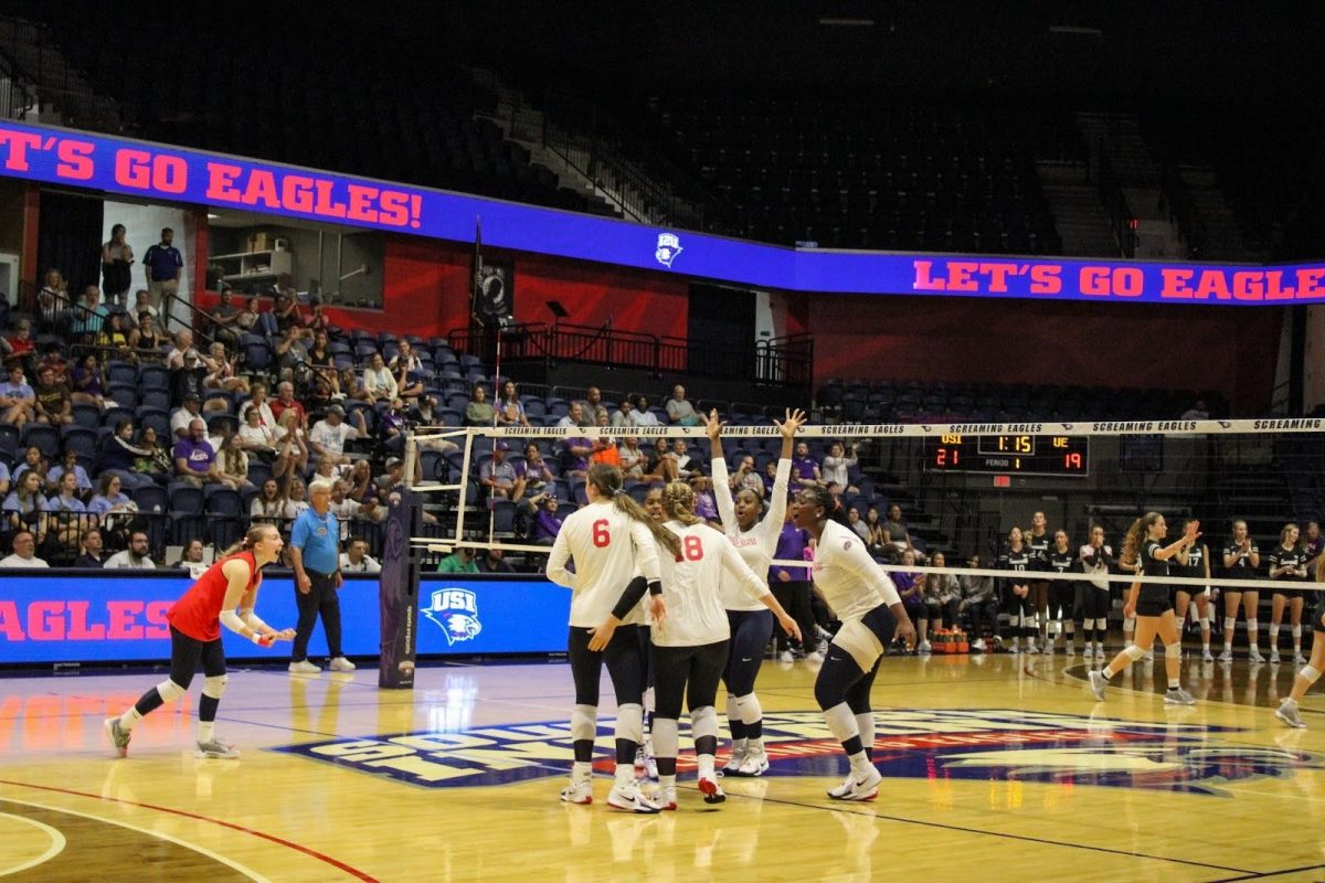 The women’s volleyball team celebrates a crucial point in the first set of the match against the University of Evansville on Friday in the Screaming Eagles Arena. (Photo by Lizzy Hannon) 
