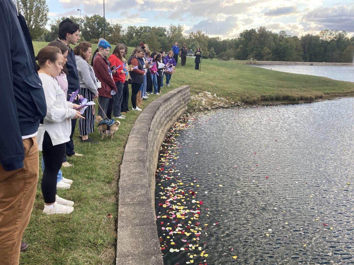 Attendees of Flowers on the Lake scatter flowers onto the Reflection Lake Tuesday in remembrance of those who have lost their lives to domestic violence. 