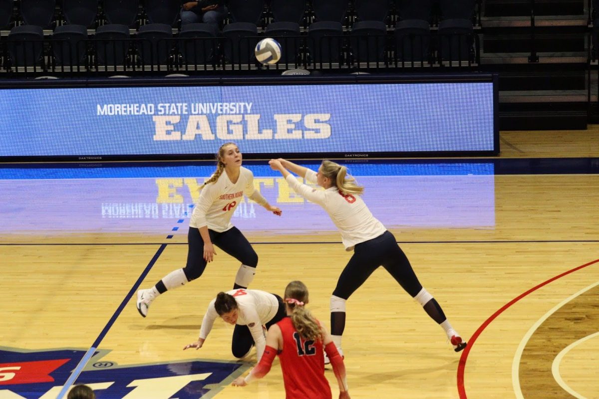 Screaming Eagles attempt to hit the ball as Kerigan Fehr, freshman libero defensive specialist, scrambles to clear out in the match against Morehead State University Friday in Liberty Arena. (Photo by Will Kessinger)
