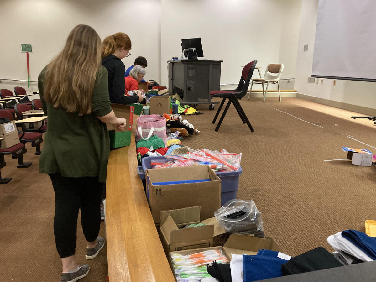 Students and volunteers from Samaritan’s Purse fill shoeboxes with hygiene supplies, school supplies, notebooks, toys and clothes Tuesday in the David L. Rice Library.