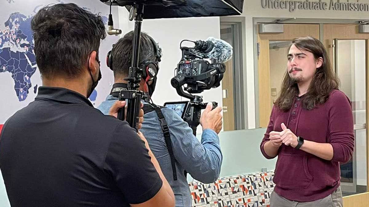 Cole Stephenson, ’22 economics and philosophy graduate, films a portion of a college tour video in front of the undergraduate admissions center. (Photo courtesy of USI Strategic Communication)
