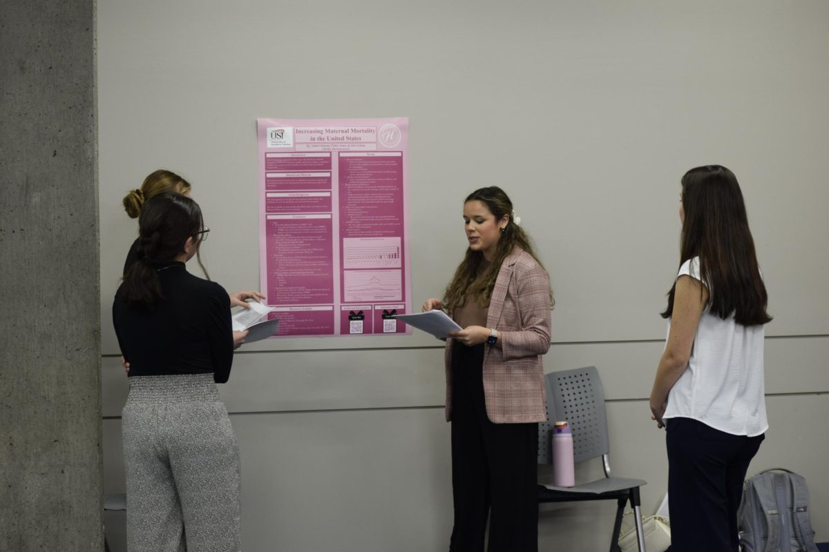 Honors students gather around Tinley Jones and Amber Duncan, senior nursing majors, to hear their presentation about maternal mortality rate in the United States at the honors student symposium in the University Center East Monday, Nov. 17. (Photo by Cade Smithson)