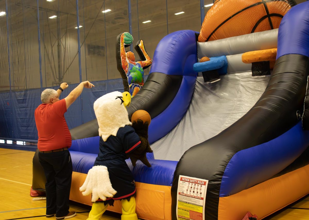The University's President Steve Bridges and Archie play head-to-head in a shooting competition at an inflatable basketball hoop at the First Friday Tailgate, Nov. 7, in Screaming Eagle Complex. (Photo by Anderson Schmidt) 