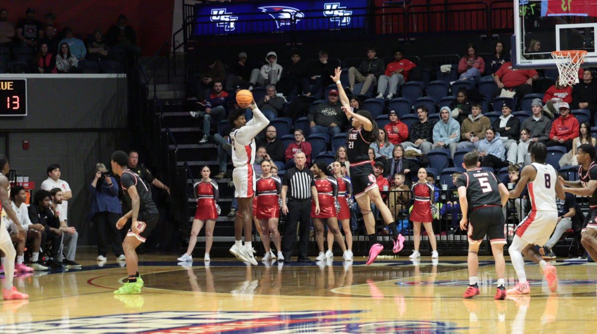 Devin Curtis, junior forward, shoots a three-pointer over a Southern Illinois University Edwardsville defender Saturday, Jan. 31, at Liberty Arena. (Photo by Anderson Schmidt)