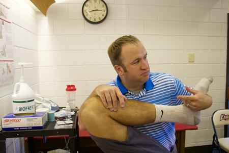 Scott Hooker, head athletic trainer, stretches out soccer player Michael Sass, a senior exercise science major.