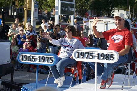 Jennifer Laval (left) and Steve Craven (right), both USI alumni, wave to the crowd as they are taken down Franklin Street on the university’s float Saturday. Laval and Craven were two of the ten university alumni and students meant to represent the five decades of the university’s existence. 